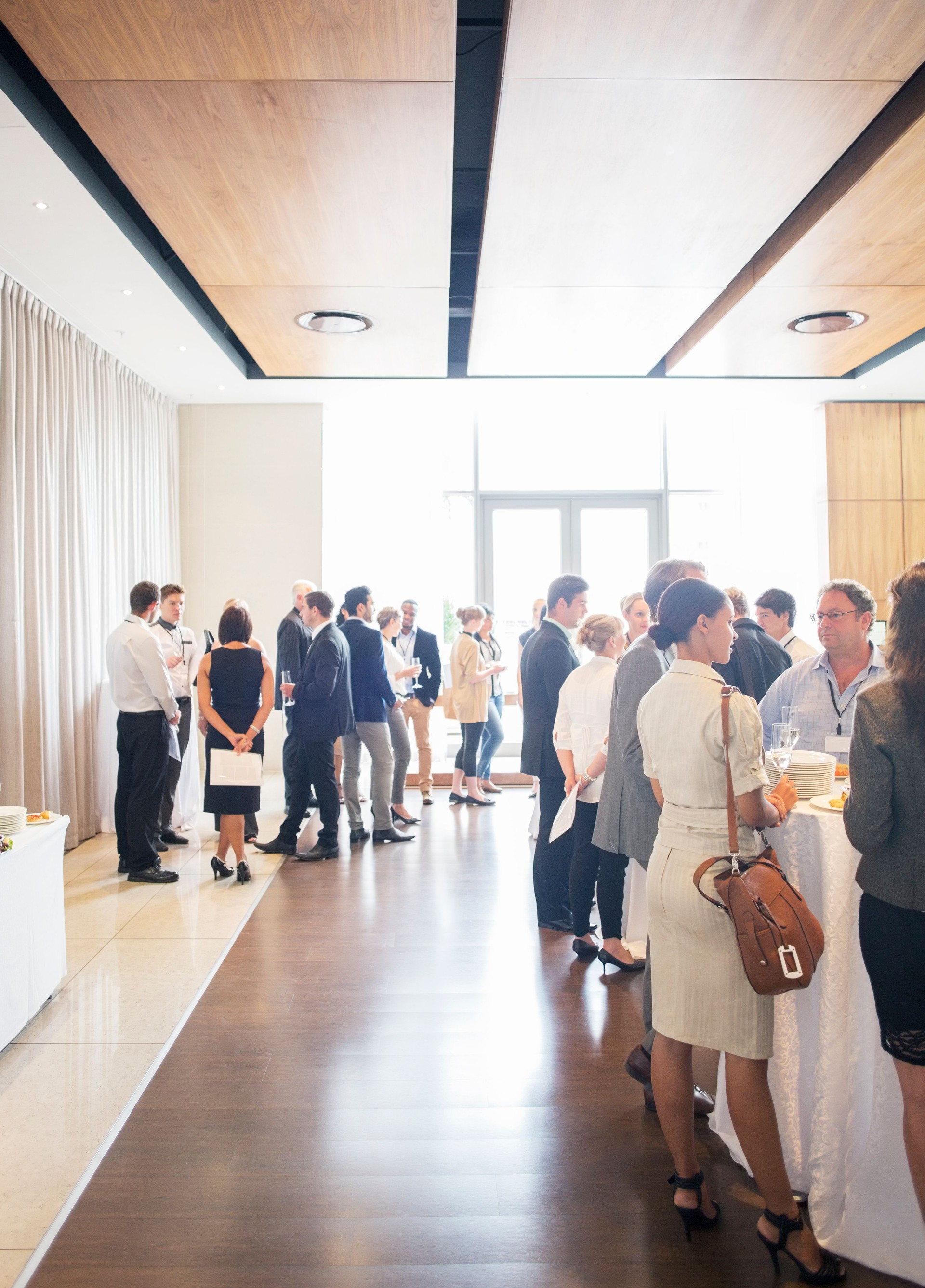 Large group of people socializing in lobby of conference center during coffee break